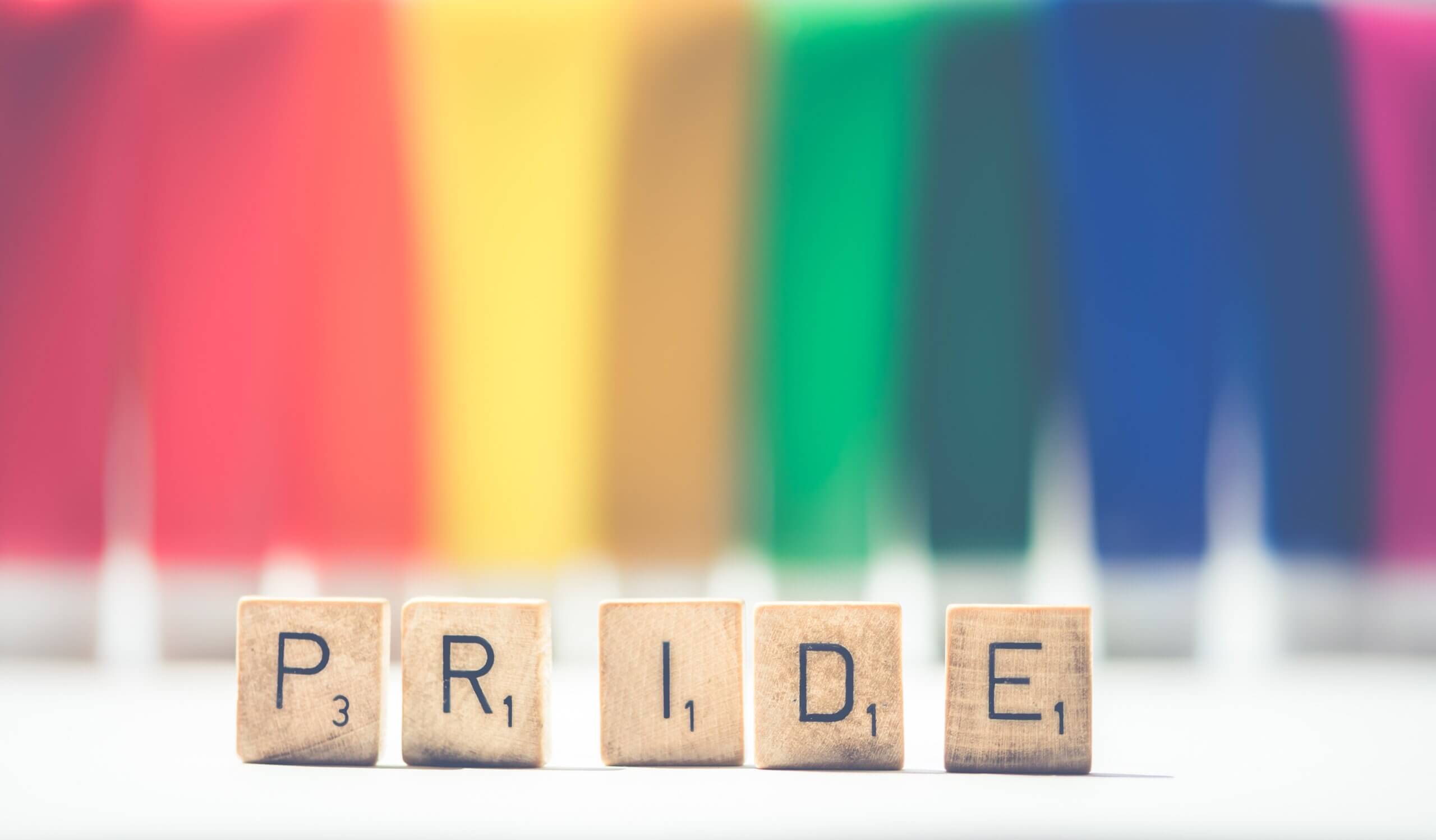pride écrit en mode scrable avec en fond les couleurs du drapeau LGBT